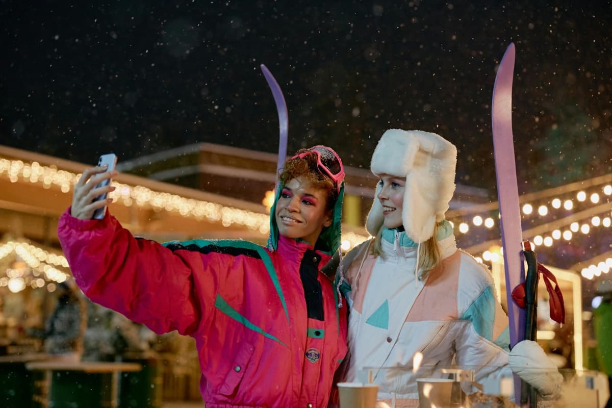 Two skiers taking a selfie at a European ski resort at night