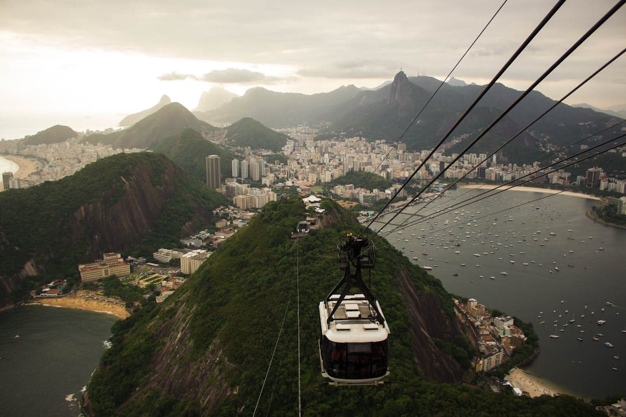 Aerial view of Rio de Janeiro with Sugarloaf Mountain cable car, lush green hills, cityscape, and Guanabara Bay at sunset