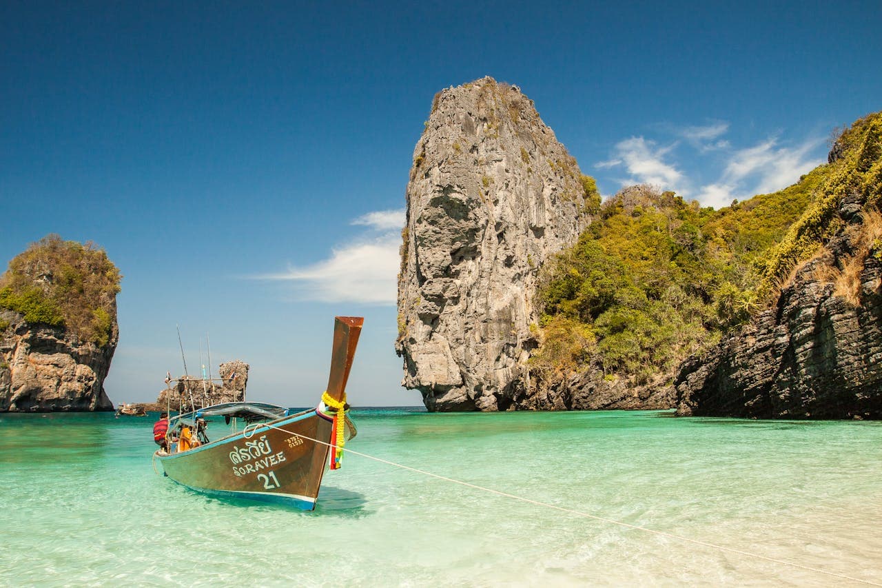 Traditional Thai longtail boat anchored in turquoise waters at a scenic limestone island beach in Thailand