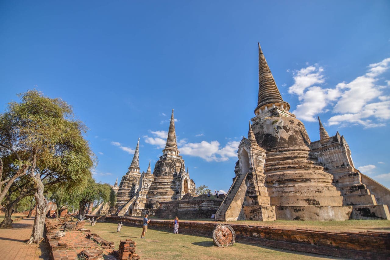 Ancient Buddhist stupas and ruins at Wat Phra Si Sanphet temple in Ayutthaya Historical Park, Thailand, under a clear blue sky.