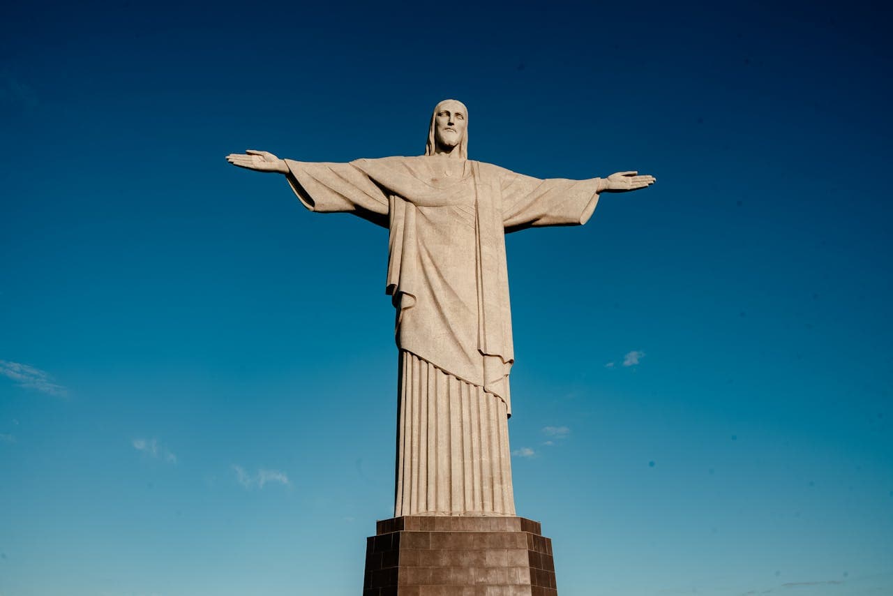 Frontal view of the Christ the Redeemer statue atop Corcovado Mountain in Rio de Janeiro against a clear blue sky