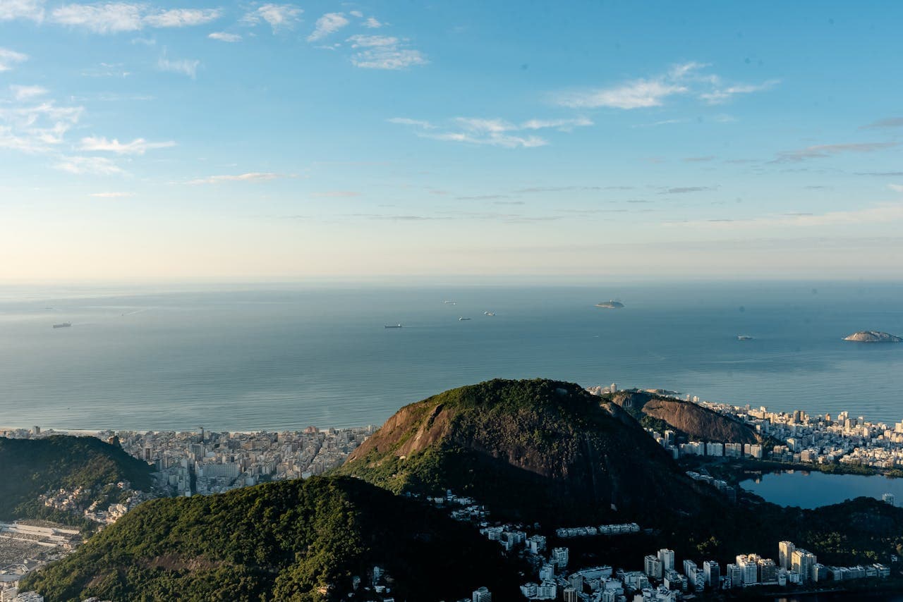 Panoramic aerial view of Rio de Janeiro’s coastline showing the lush green hills of Tijuca Forest, cityscape and cargo ships in Guanabara Bay