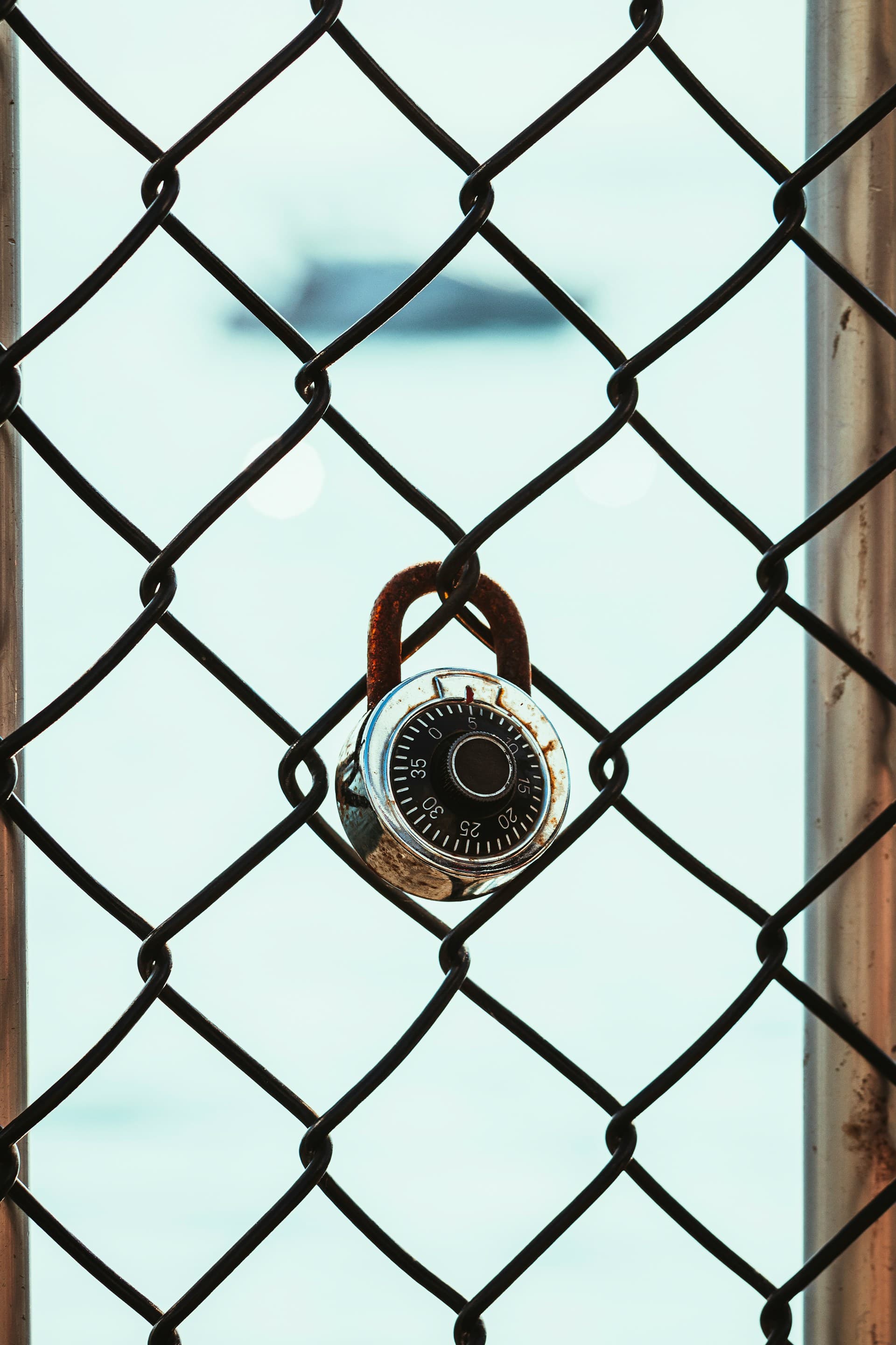 A combination lock on a fence, representing how Belgian mobile operators lock users to a single network with no option to switch for better mobile coverage