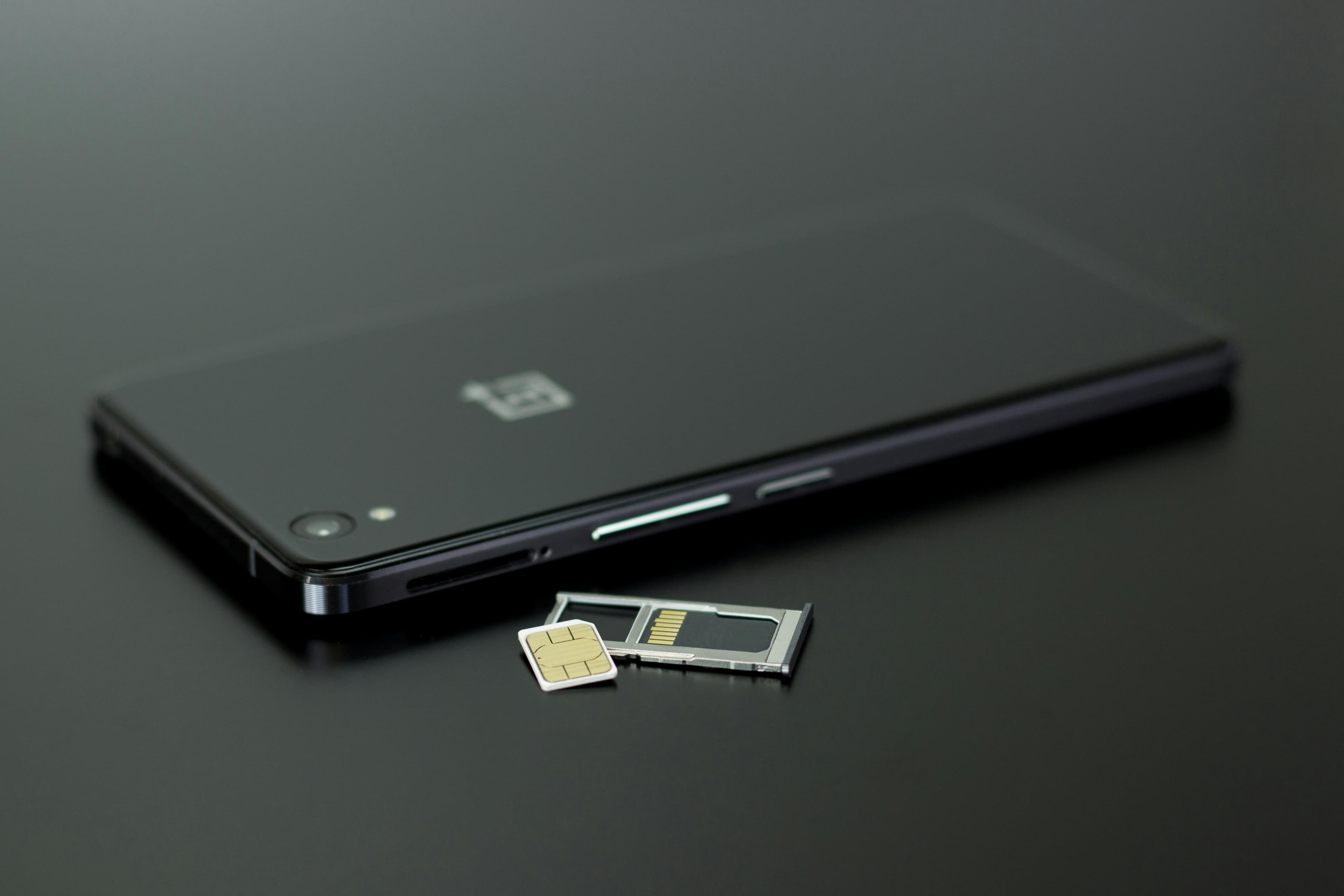 Smartphone beside a removed SIM card and its tray