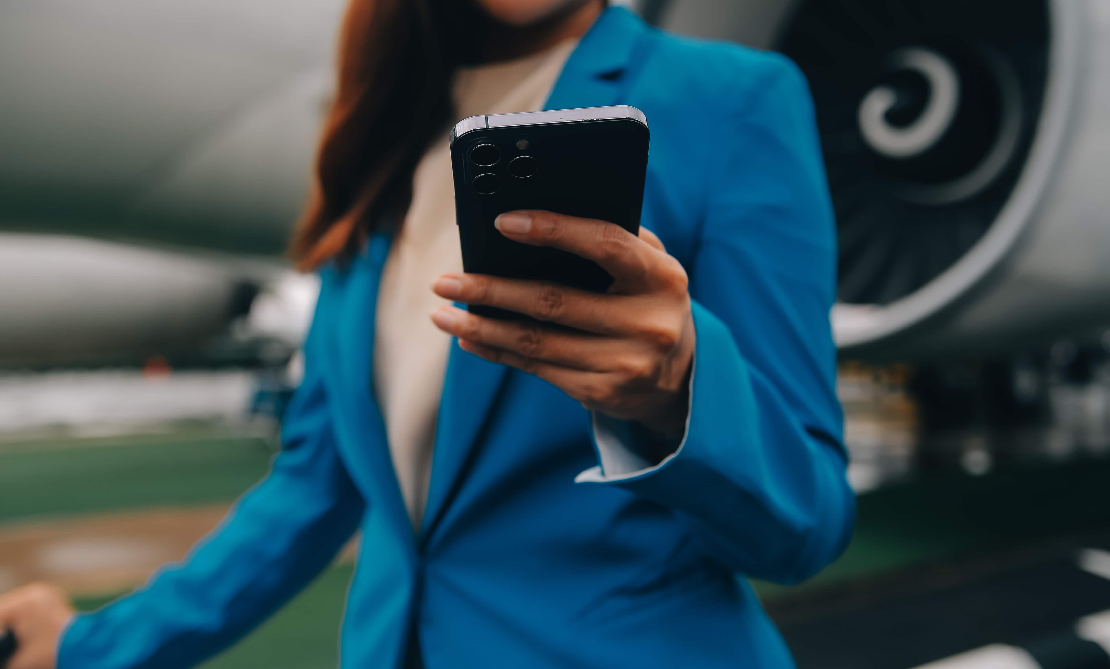 Flight attendant checking her phone on the airport tarmac