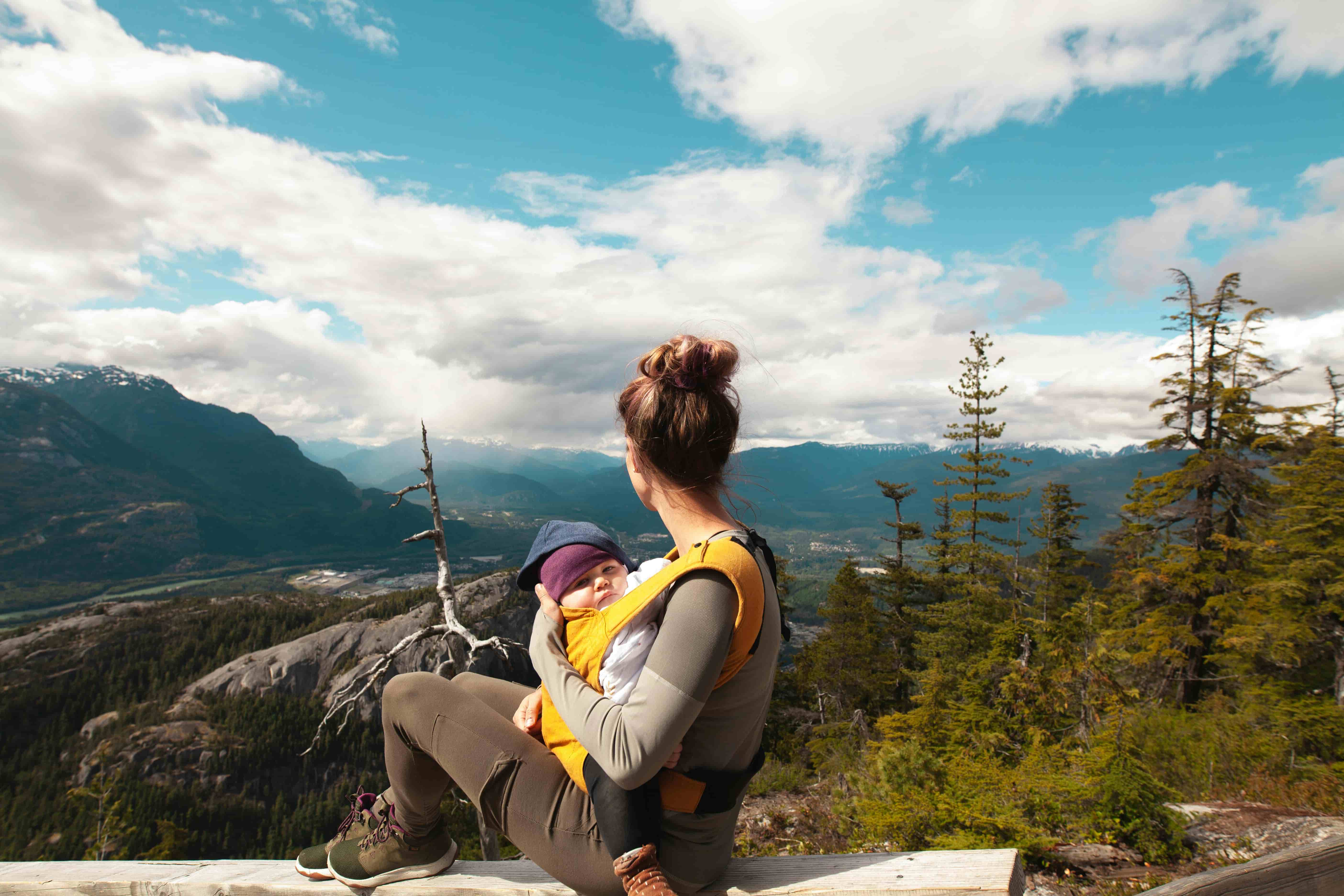 Parent hiking with a baby carrier overlooking mountains in Europe