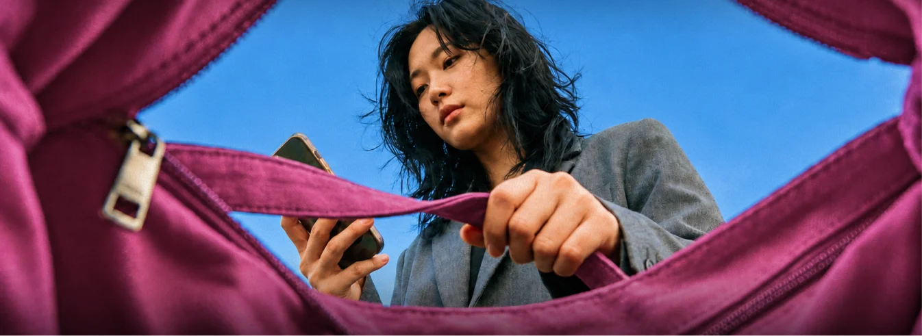 A woman reading her phone, seen from inside the bag she is reaching into