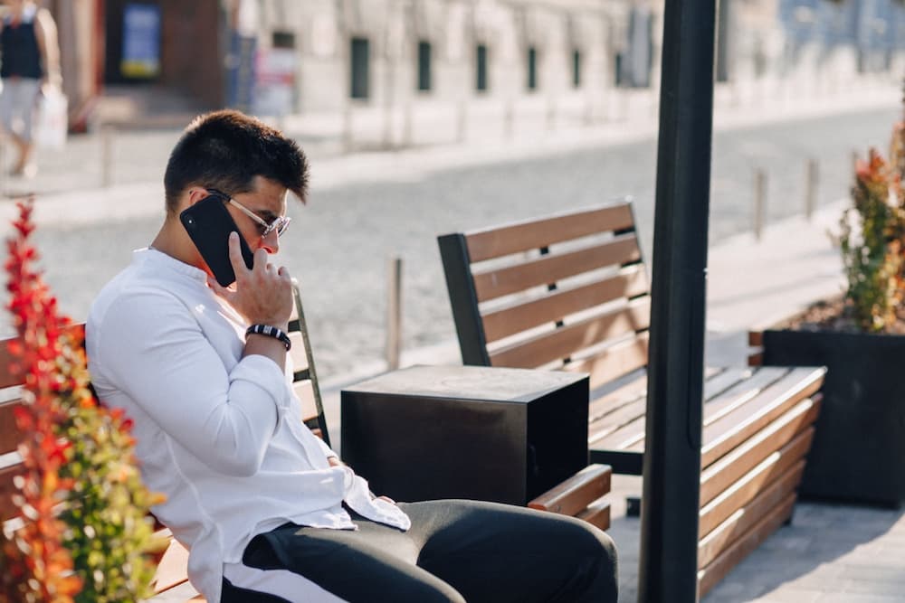 man on a bench making really cheap international calls using Firsty