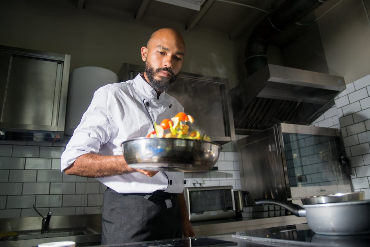 A chef in a kitchen cooking portuguese dishes on a pan.