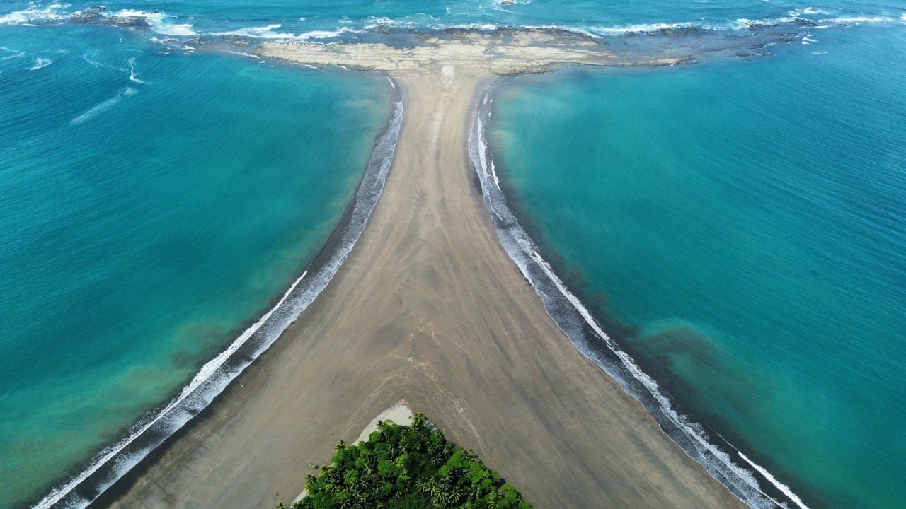 Aerial view of the stunning T-shaped beach formation at Playa Uvita, Costa Rica, where two ocean tides meet along a natural sandbar