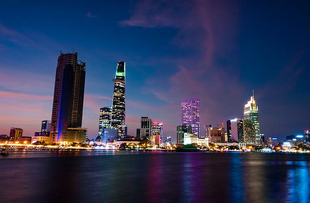 Night view of Ho Chi Minh City skyline with illuminated skyscrapers reflecting on the Saigon River in Vietnam