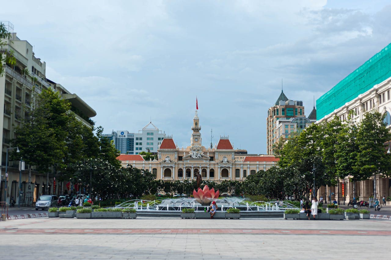 Front view of the historic Ho Chi Minh City Hall, also known as the People’s Committee Building, with a lotus fountain and tree-lined Nguyen Hue walking street in the foreground.
