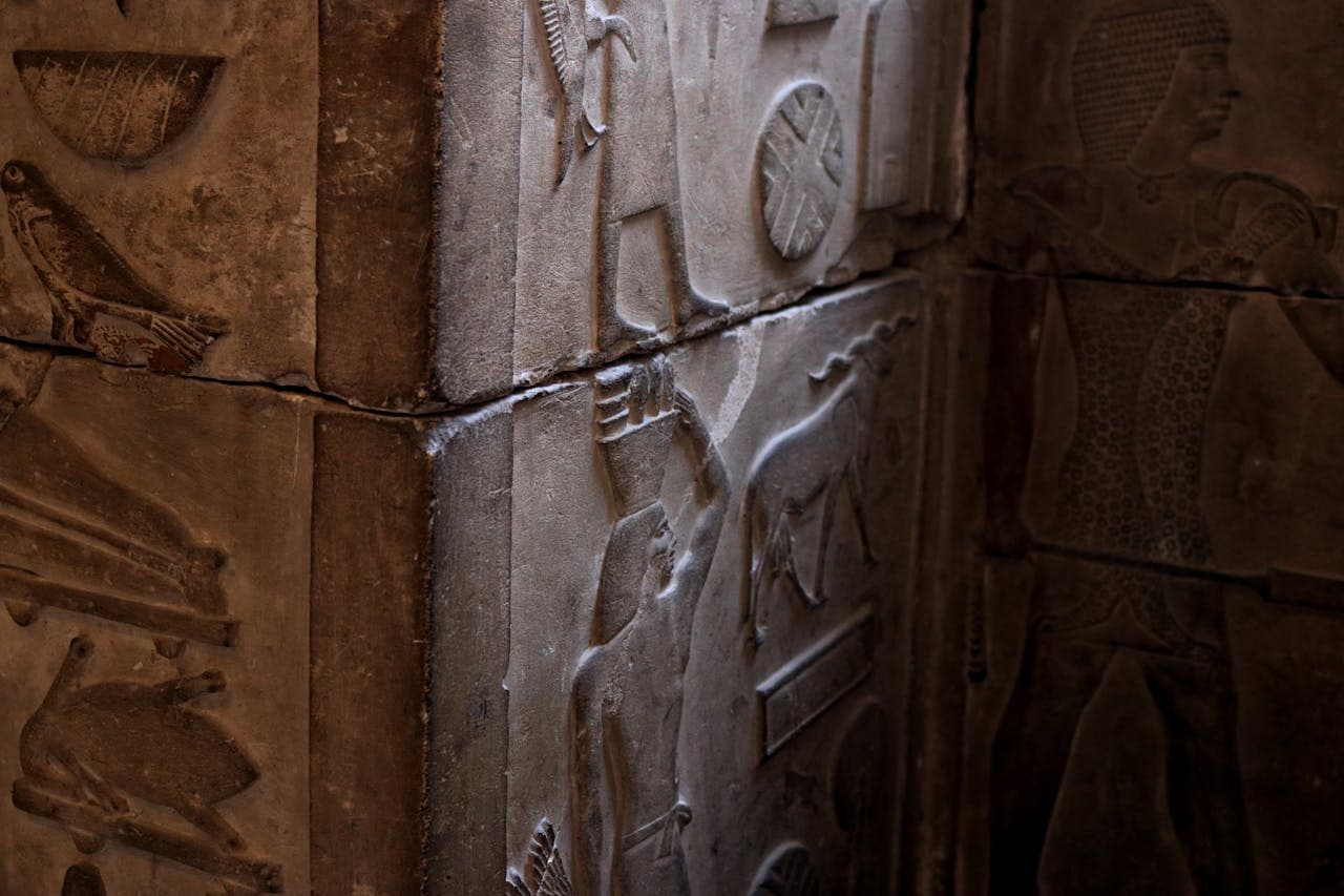 Close-up of ancient Egyptian hieroglyphs and carvings on stone walls inside a historic temple or tomb