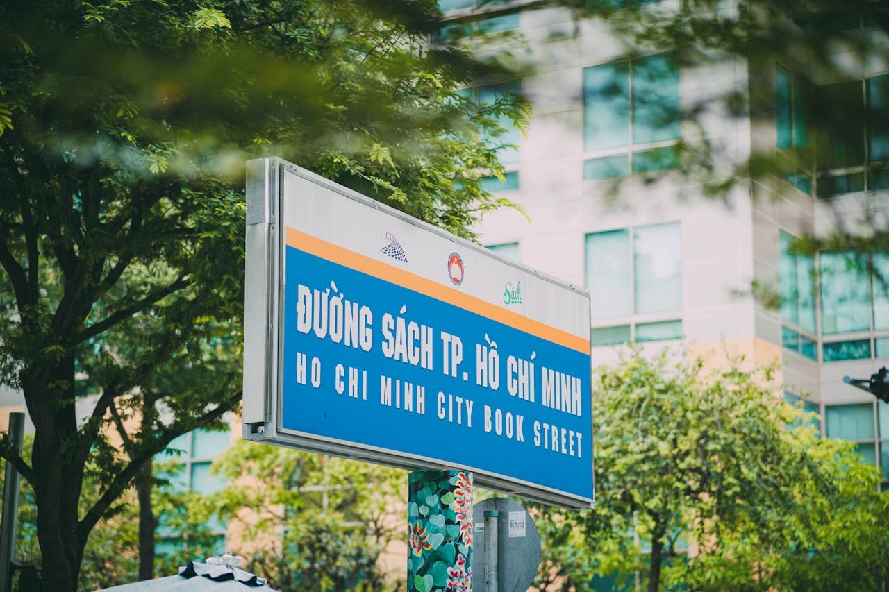 Sign for Ho Chi Minh City Book Street in Vietnam with modern buildings and green trees in the background