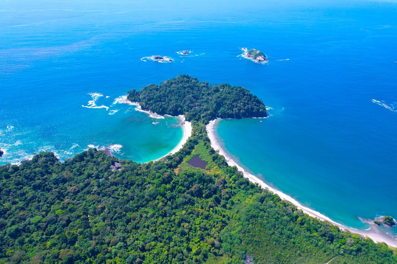 Drone shot of Costa Rica’s dense tropical rainforest meeting clear blue Pacific Ocean waters, highlighting the untouched Osa Peninsula coastline and vibrant green canopy.