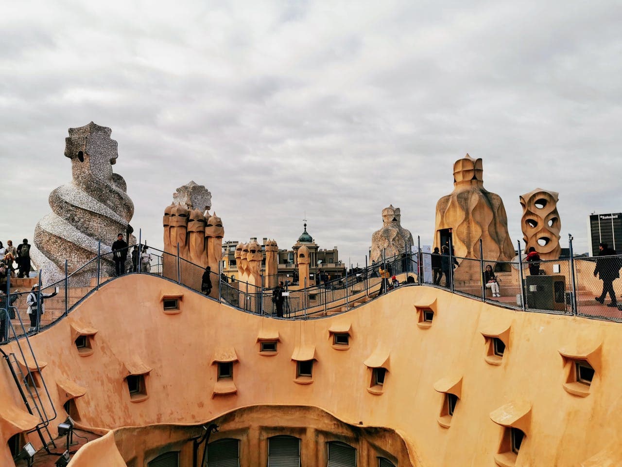 Rooftop of Casa Milà (La Pedrera) in Barcelona, Spain, featuring iconic Gaudí-designed chimneys and tourists exploring the architectural landmark.
