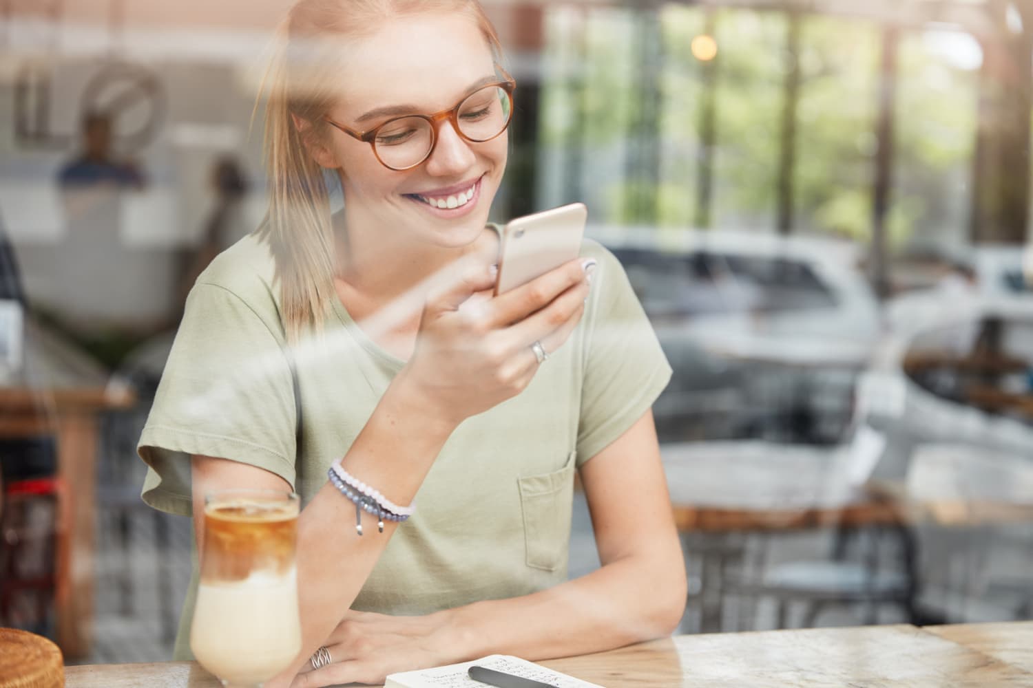 Woman smiling at her phone in a cafe, enjoying free mobile data