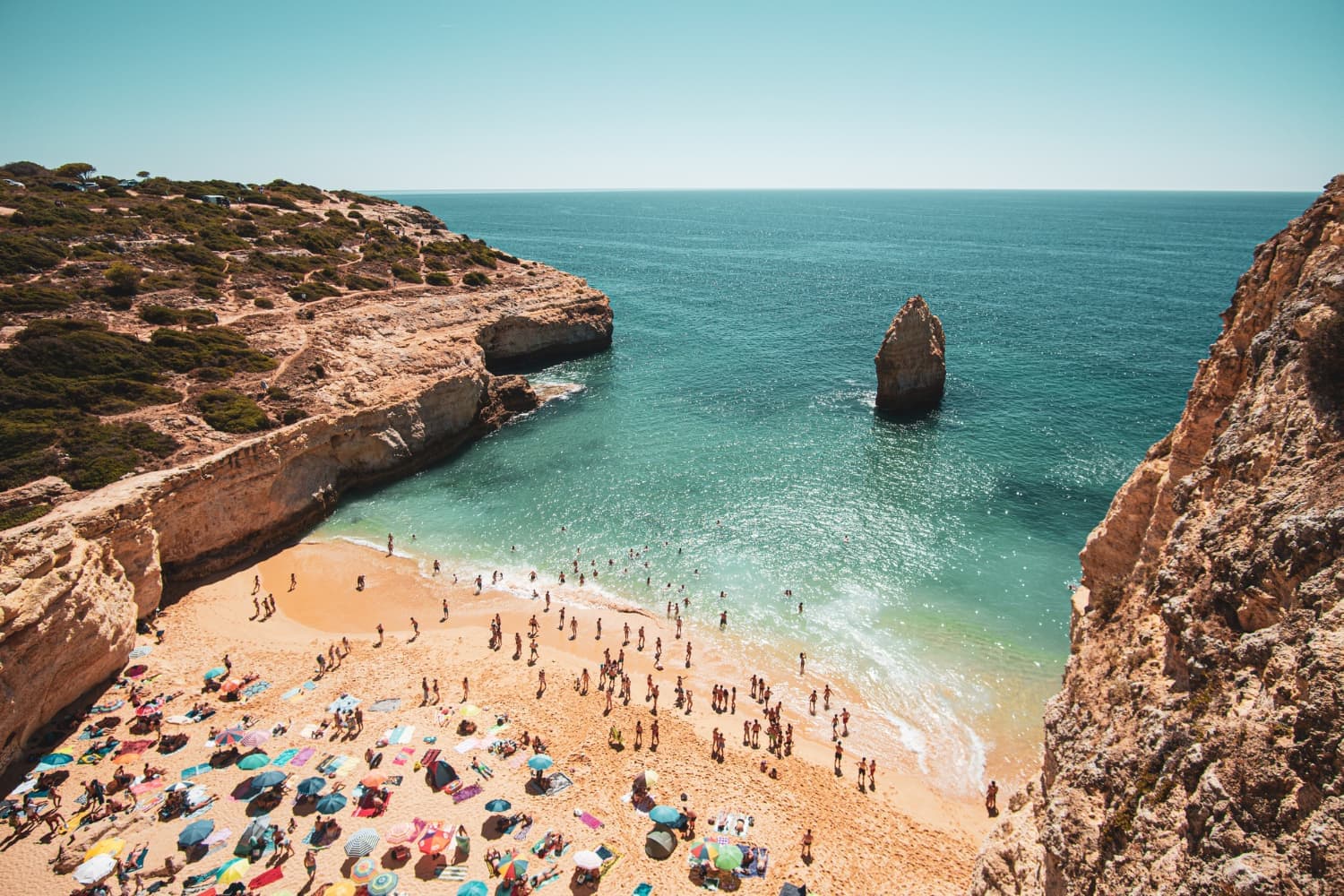 Crowded sandy beach in Polignano a Mare coastal town in Puglia Italy with limestone cliffs, Adriatic Sea views, and stunning beaches in southern Italy