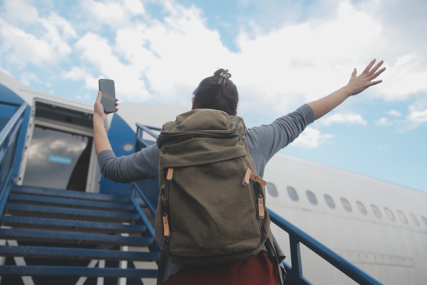 Traveller with a backpack cheering while boarding a plane