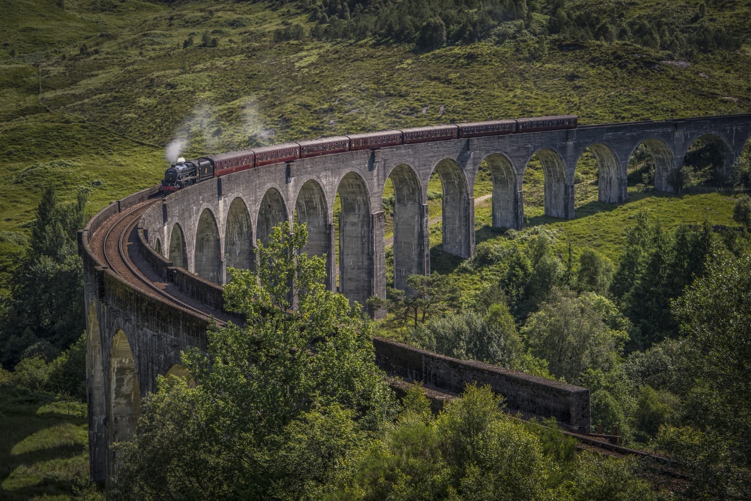 Steam train crossing the Glenfinnan Viaduct in the Scottish Highlands