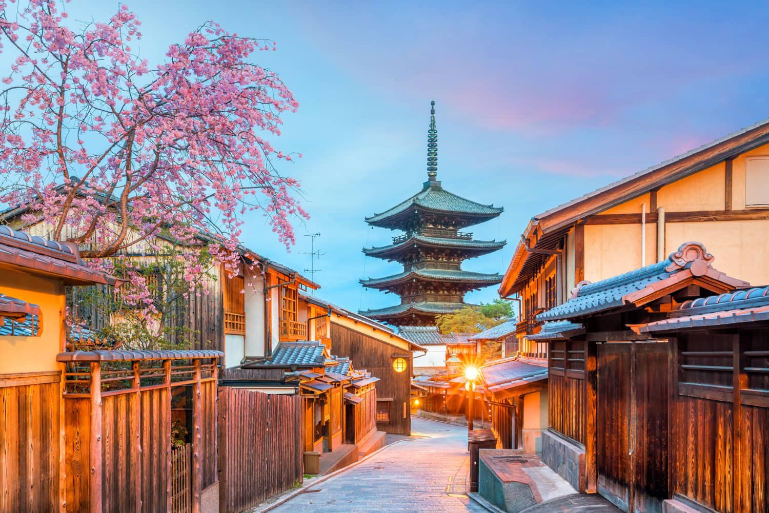 Scenic view of Kyoto’s historic streets with traditional wooden houses and pagoda at sunset.