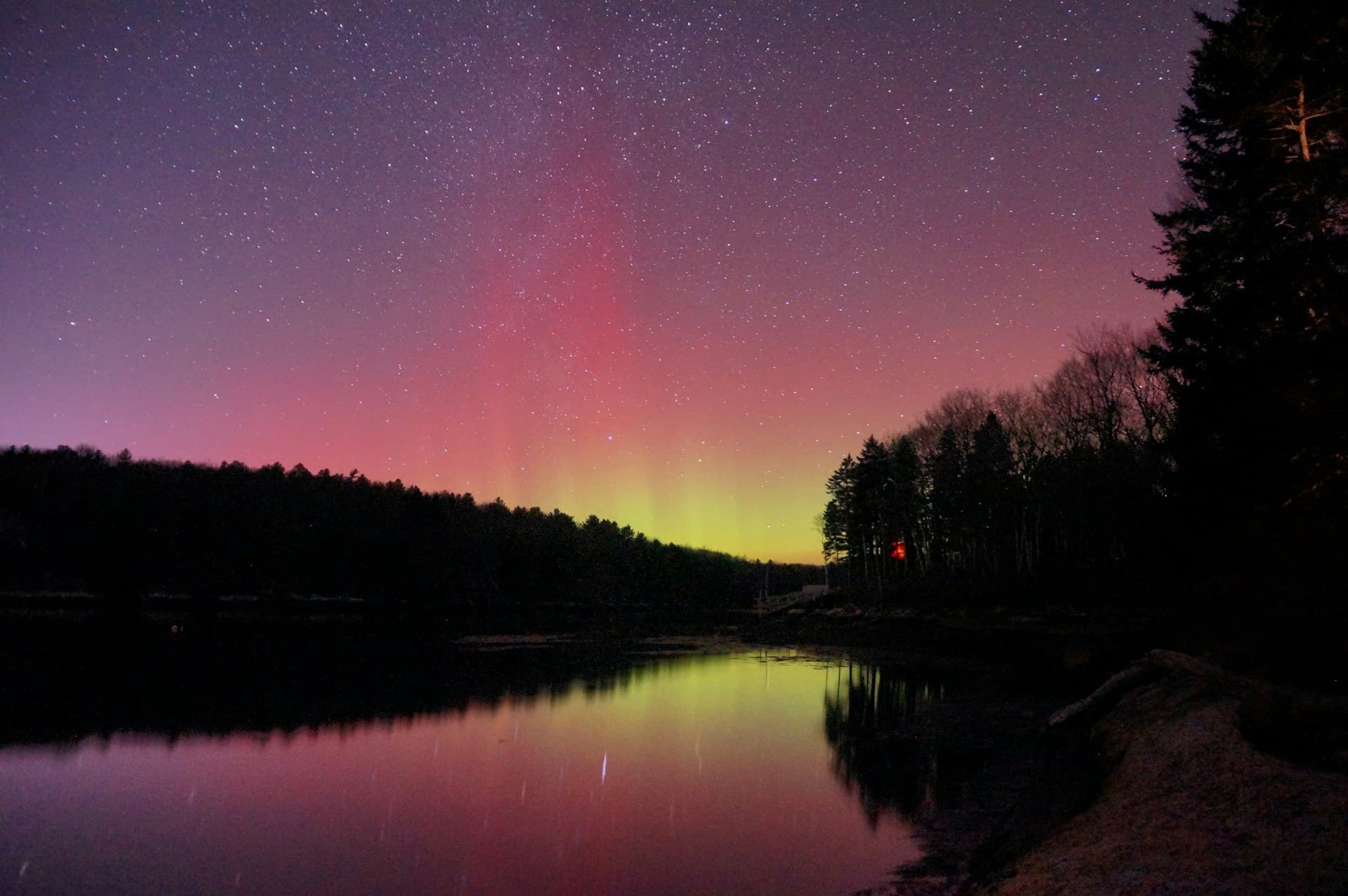 Pink and purple northern lights reflected on a lake in Maine