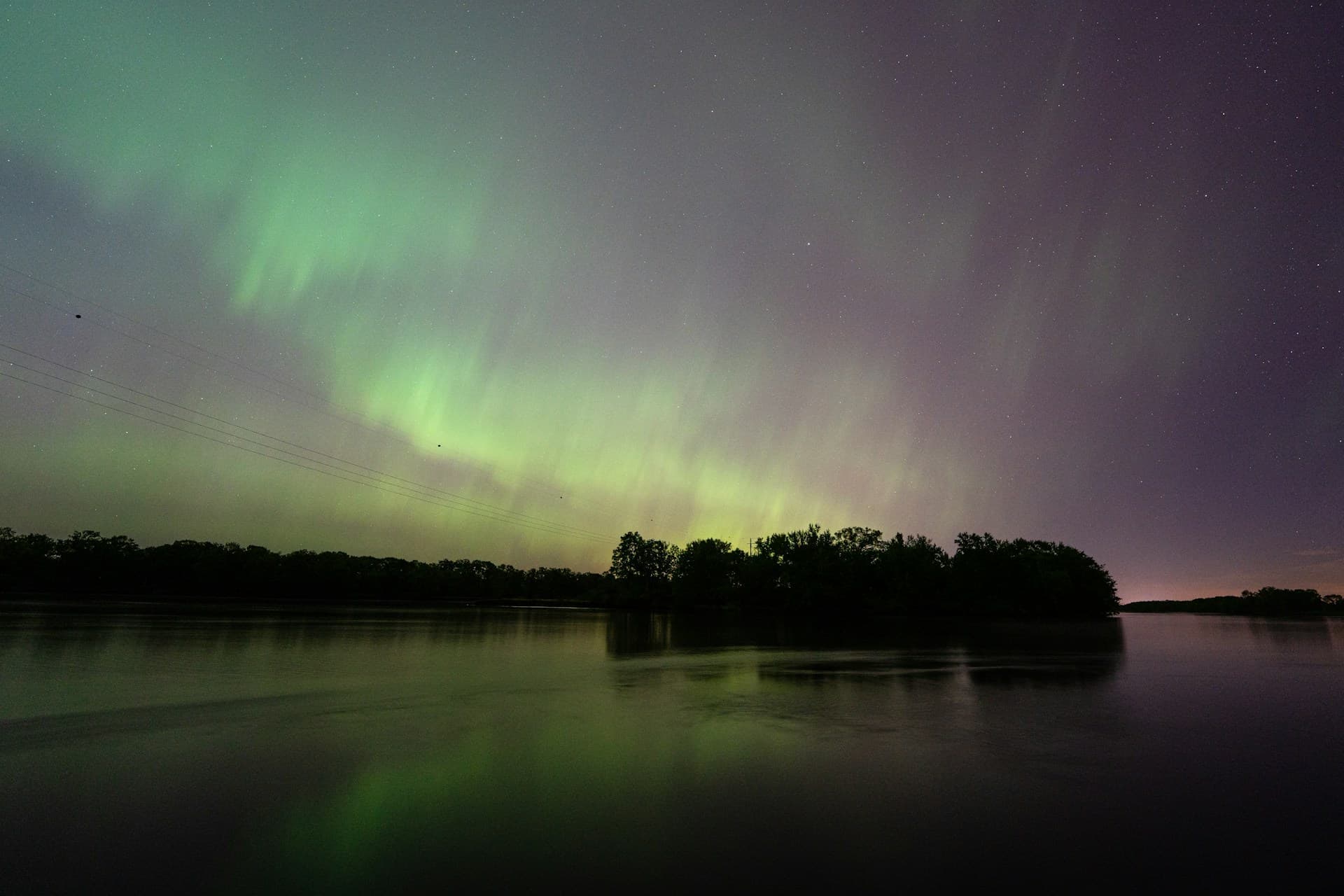 Green northern lights reflected over a lake in Wisconsin