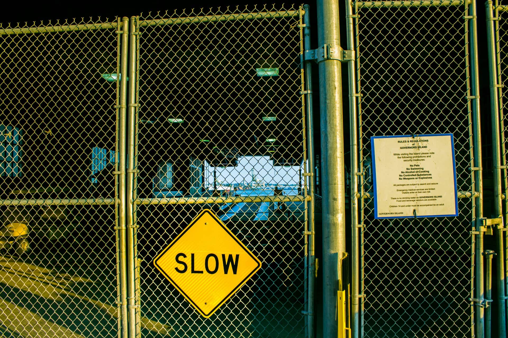 Yellow SLOW sign attached to a chain-link fence