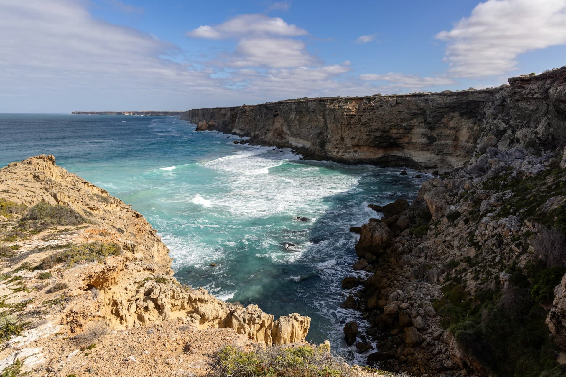 Rugged coastal cliffs and turquoise waves along a rocky shoreline
