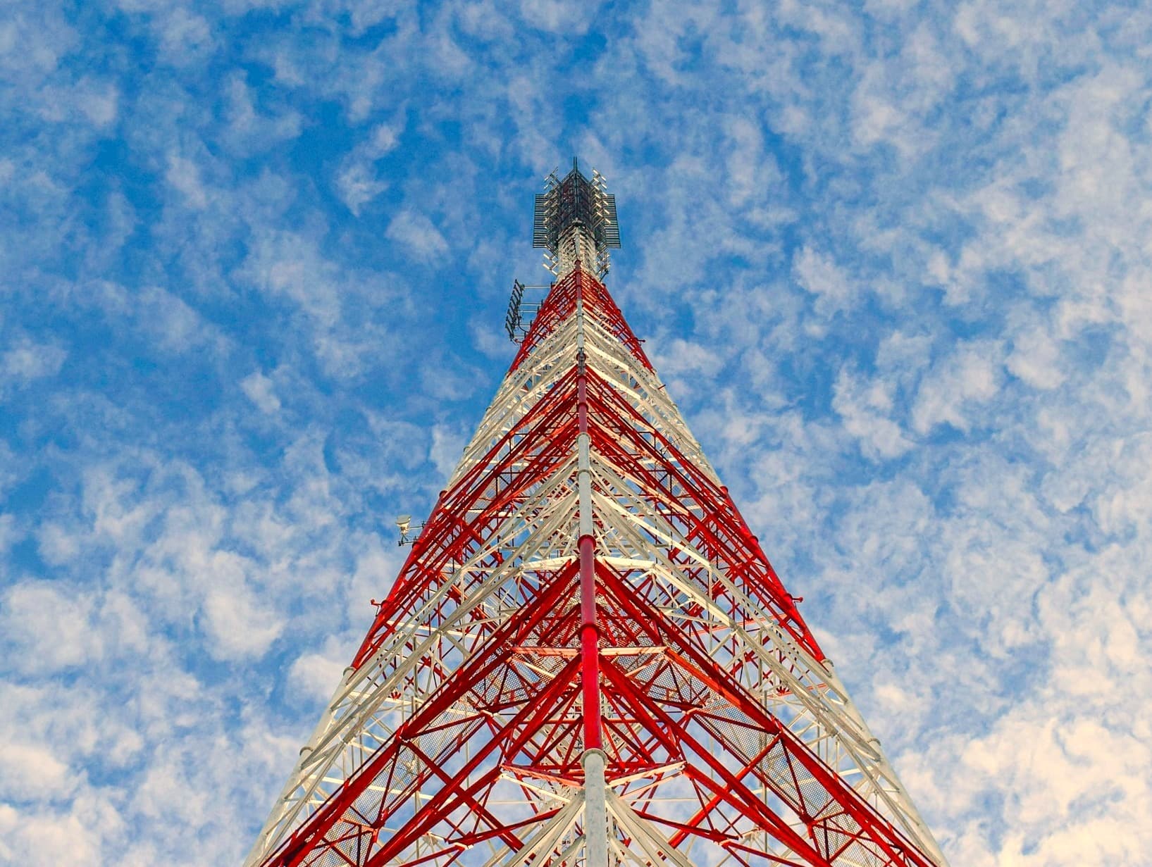 `Red and white mobile network tower against a blue sky, illustrating the single-operator infrastructure behind a Telenet outage in Belgium`