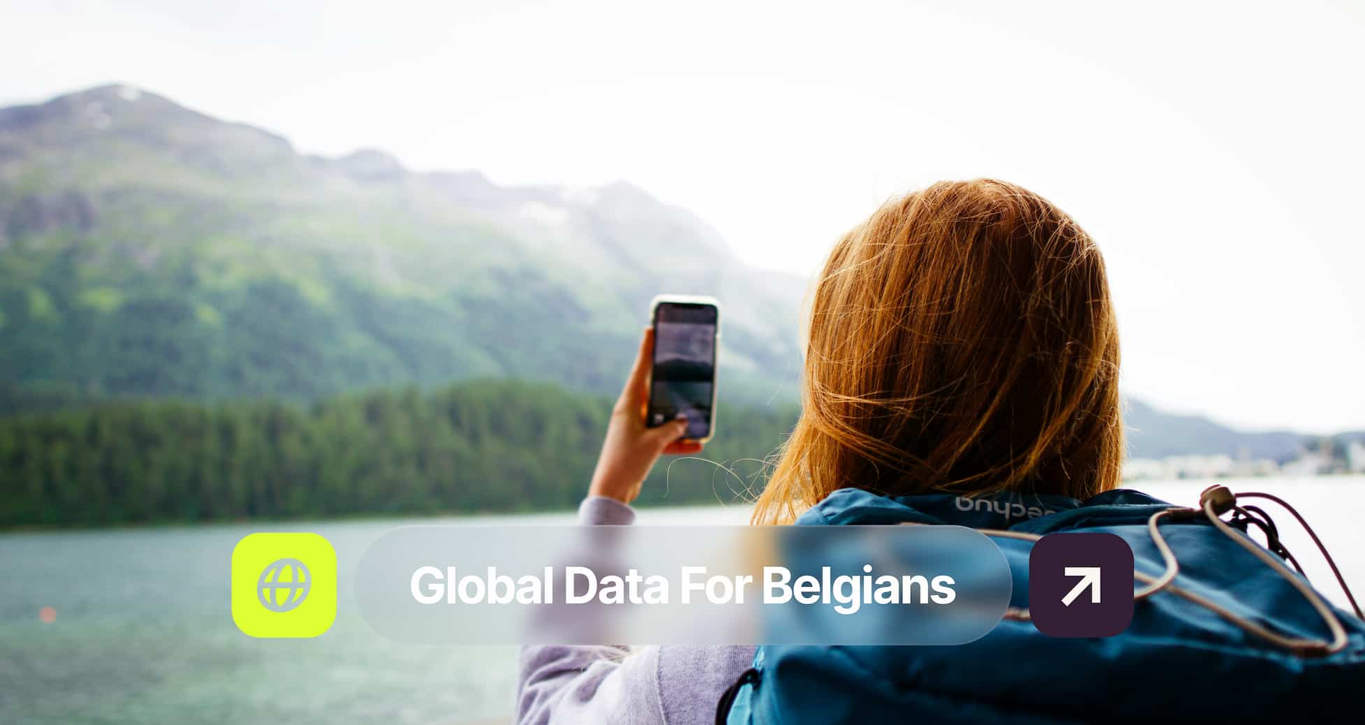 A person with a backpack takes a photo of a mountain lake with a smartphone. Text overlay reads "Global Data For Belgians" with an arrow icon.