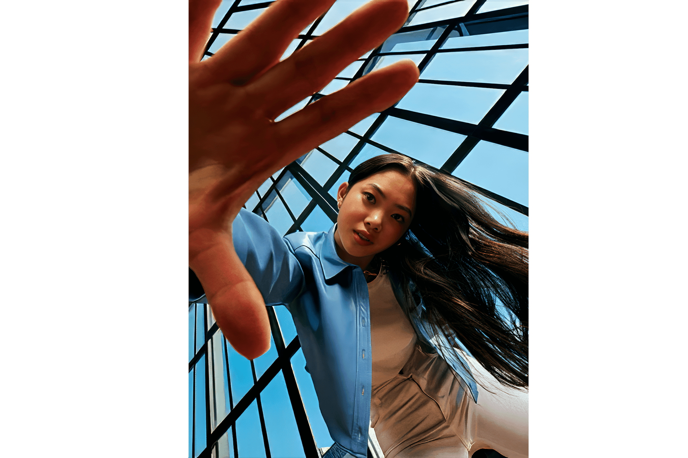 Woman reaching toward the camera under a glass atrium roof