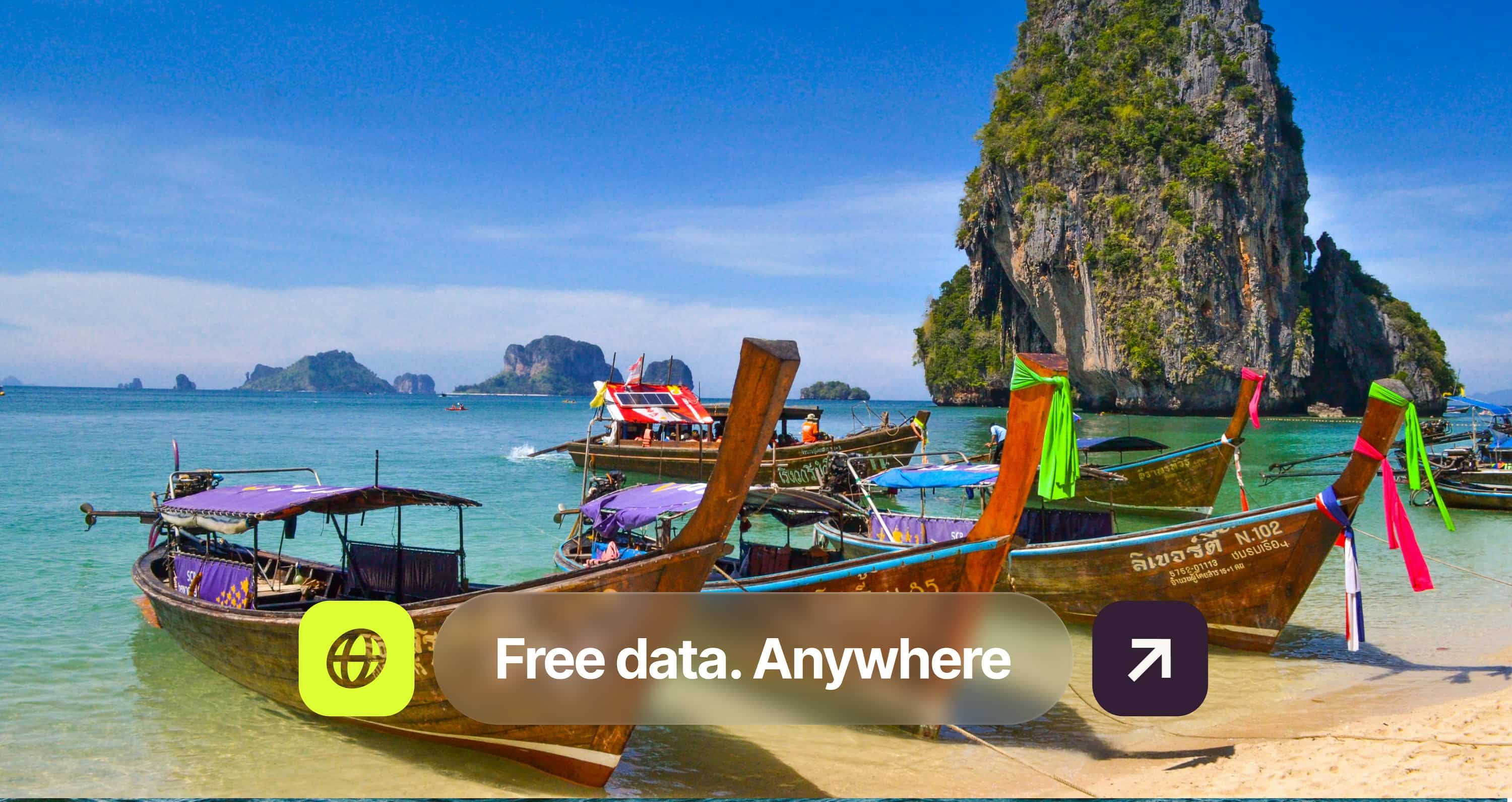 Long-tail boats docked on a tropical beach with clear turquoise water and limestone cliffs in the background. Text overlay: "Free data. Anywhere."
