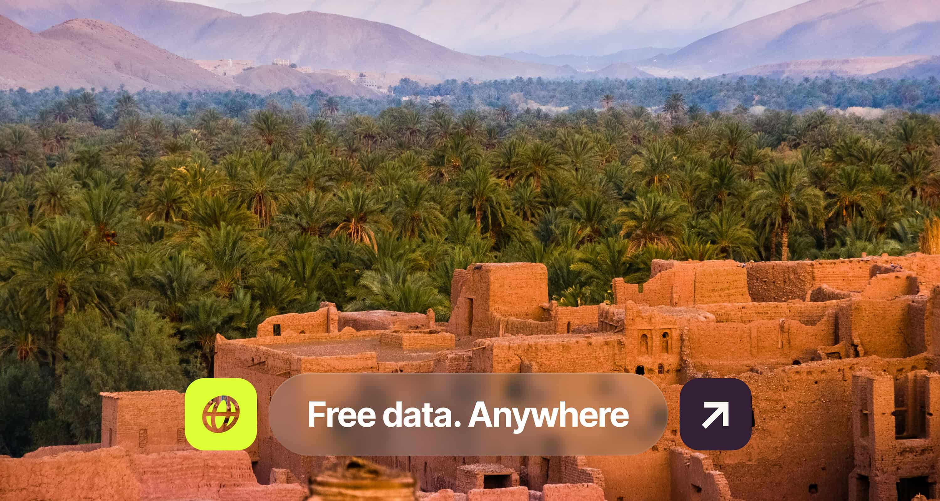 Ancient mud-brick buildings in front of a dense palm grove, with mountains in the background and text overlay: "Free data. Anywhere".