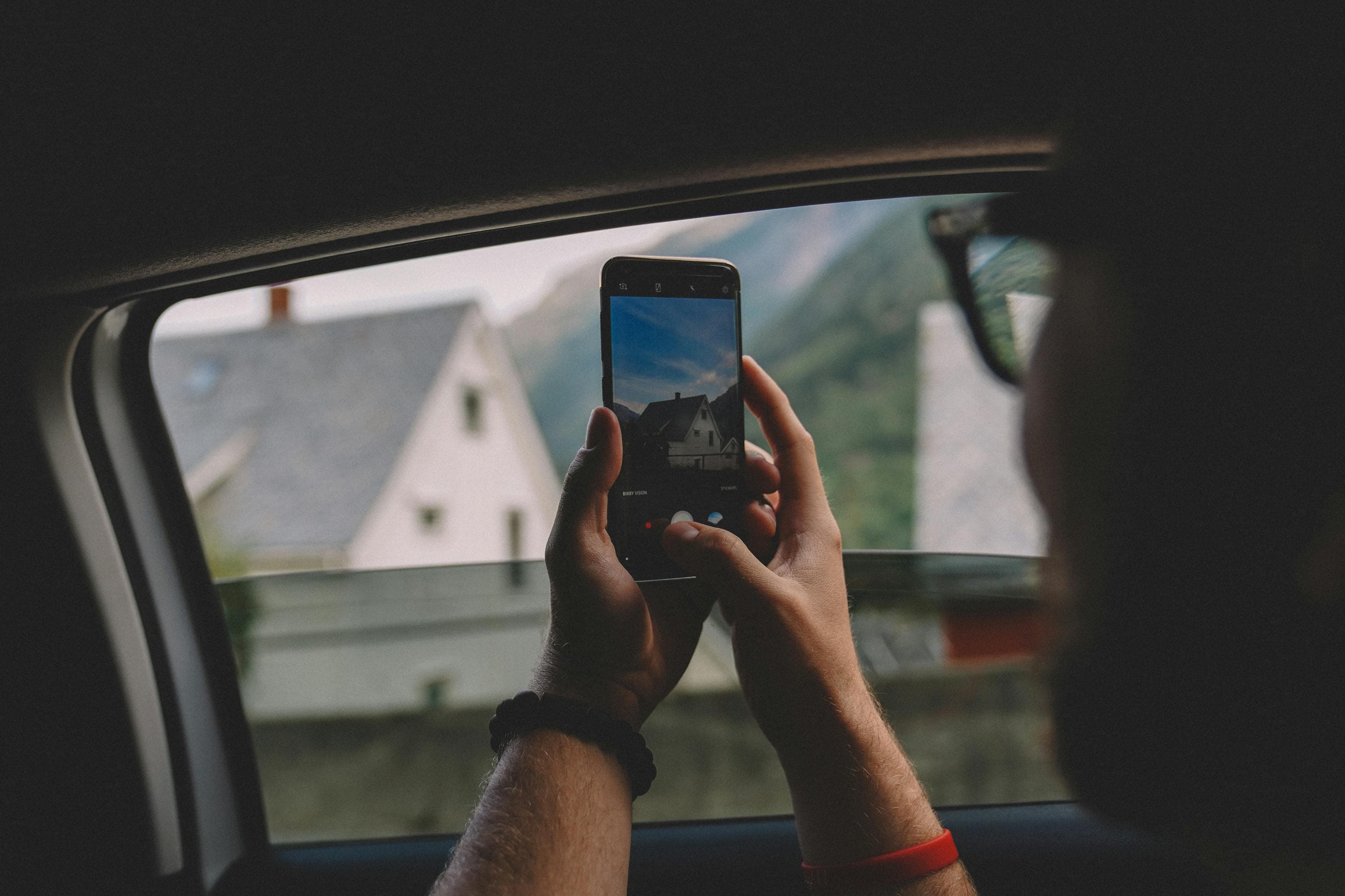 Passenger photographing mountain scenery through a car window