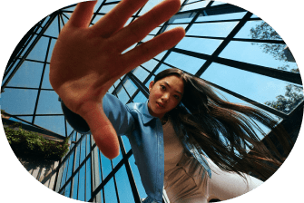 Woman reaching a hand toward the camera under a glass atrium roof