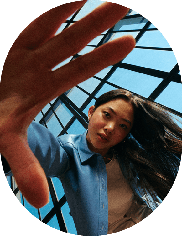 Woman reaching a hand toward the camera under a glass atrium roof