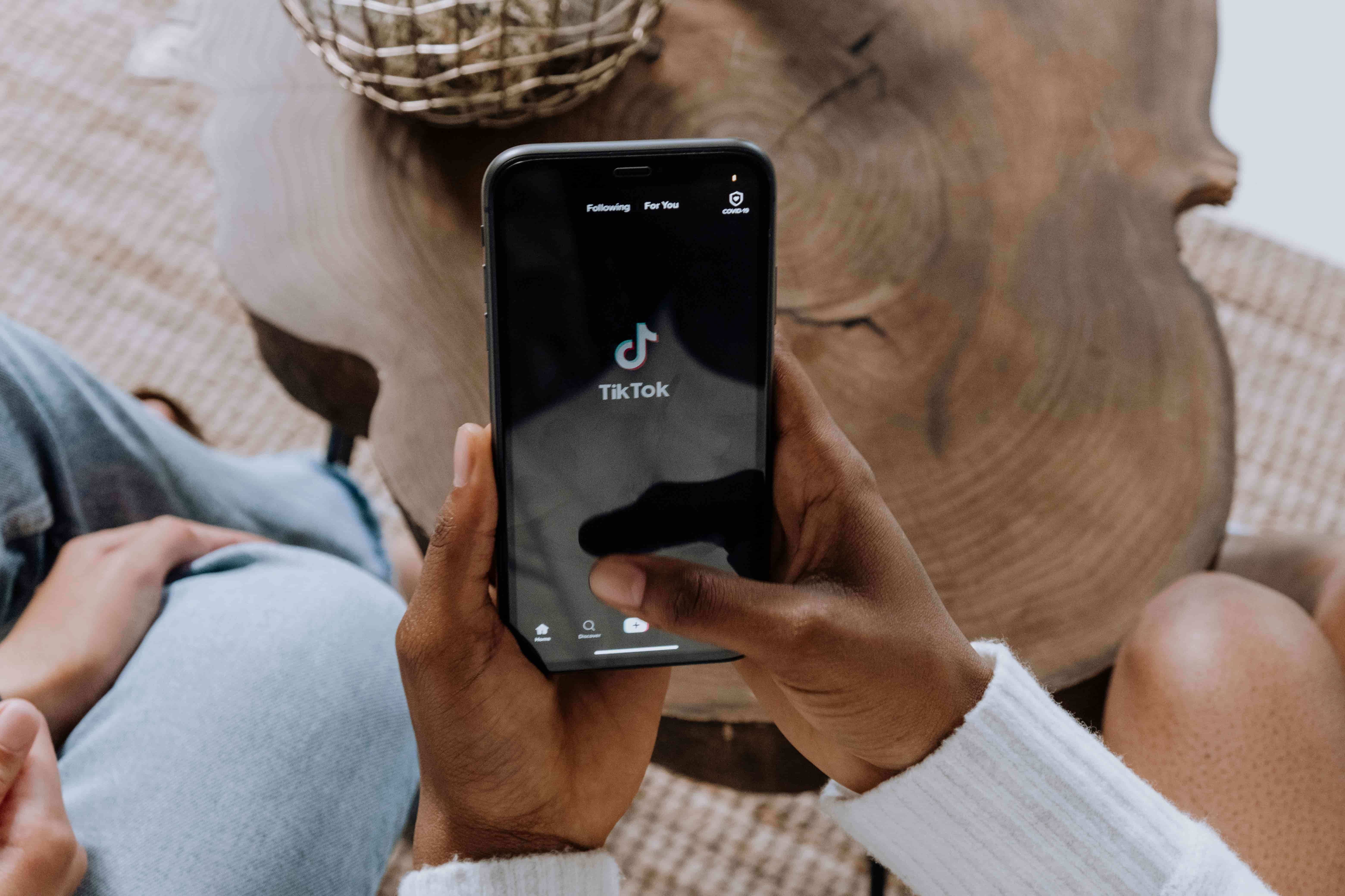 Hand holding a phone open to the TikTok app