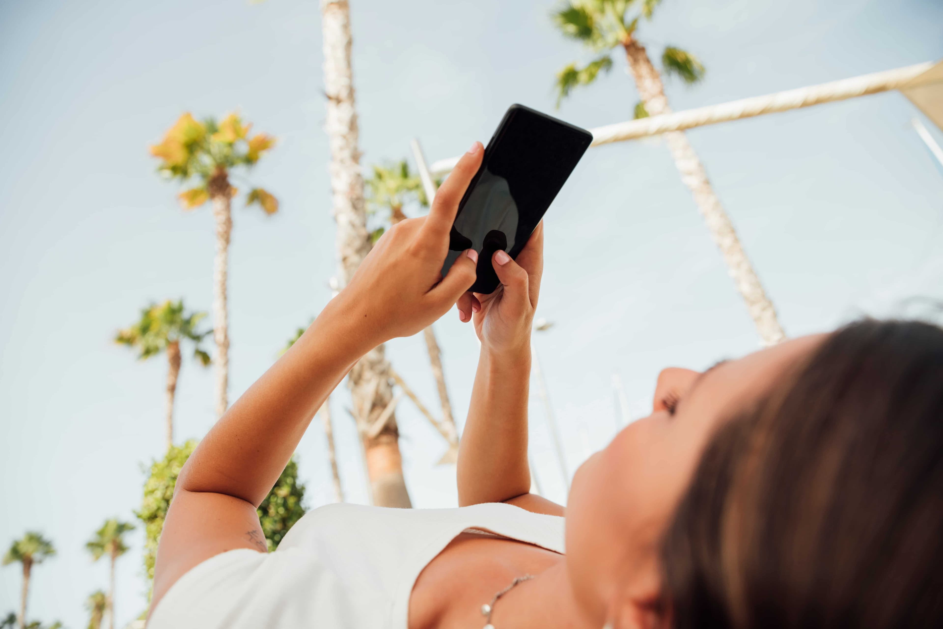 Woman checking her phone among palm trees