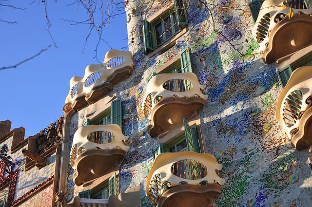 A close-up of the colorful and ornate façade of Casa Batlló, a famous modernist building in Barcelona designed by Antoni Gaudí, showcasing its unique balconies and mosaic tiles under a clear blue sky.