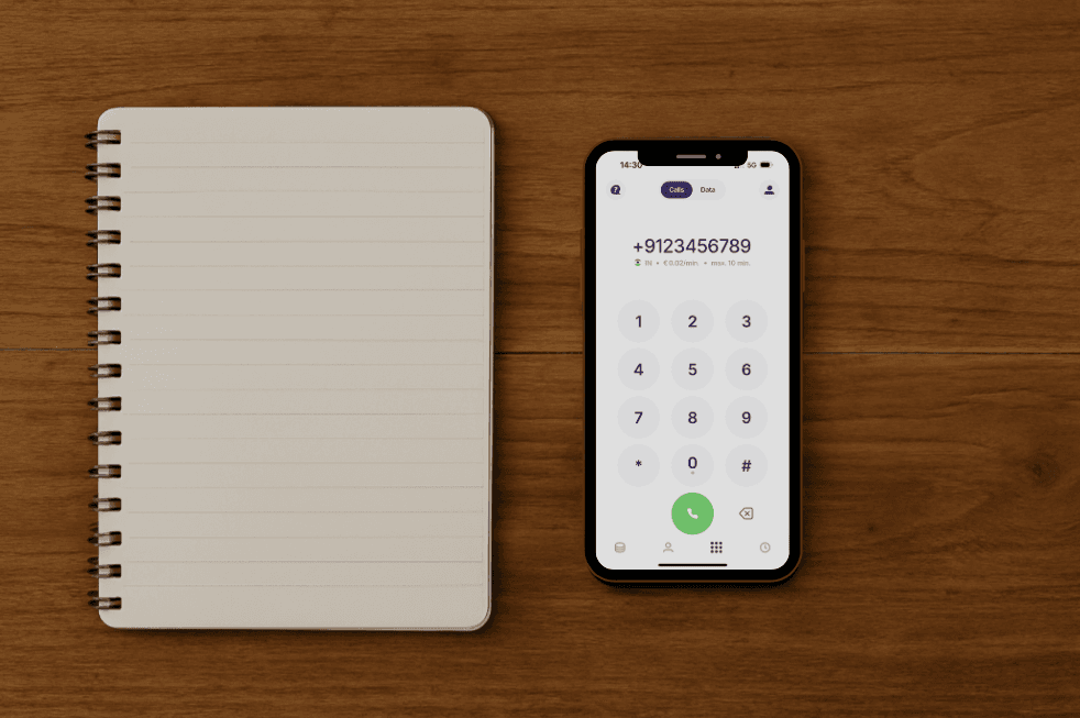 Open notebook and smartphone with dial screen on a wooden surface, showing cheap calling to india